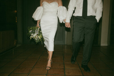 bride and groom holding hands walking into room