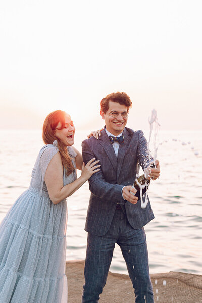 A couple pops champagne during their sunrise engagement session in Chicago