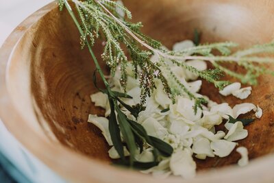 A wooden bowl with flower petals and  leaves