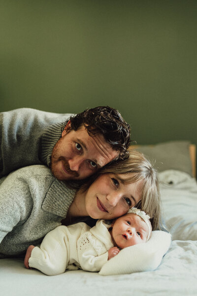 Mother holding newborn with two siblings smiling close - family newborn photography in Maple Grove Mn studio
