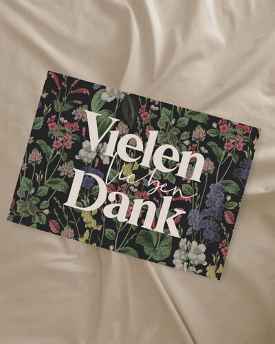 Postkarte mit den Worten „Vielen lieben Dank“ und bunten Blumen auf schwarzem Hintergrund