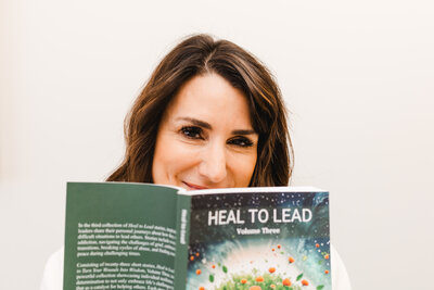 Dena smiling while holding the book Heal to Lead