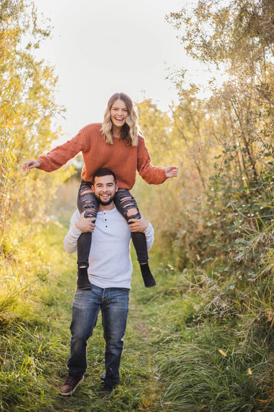 couple laughing girl on guys shoulders during engagement session