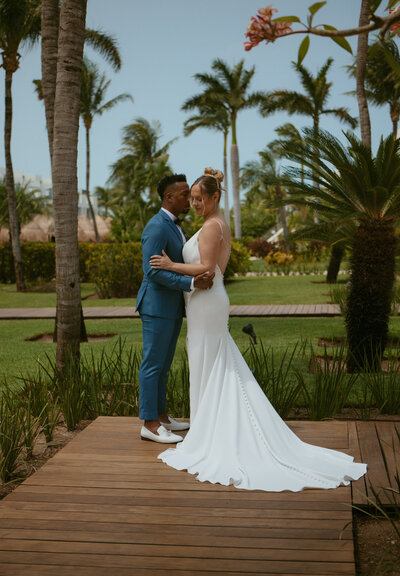 Bride and groom standing together in a lush grove of tropical trees in Mexico, sharing a quiet moment surrounded by nature