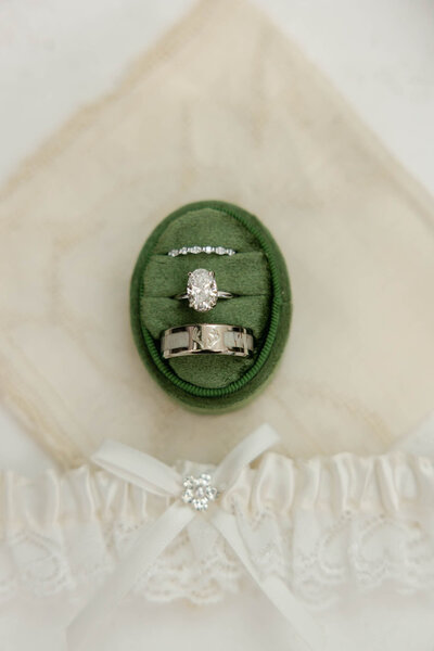 Sentimental details taken on the wedding day. A couple's ring set in a green velvet ring box sitting upon a loved one's handkerchief - their something old.
