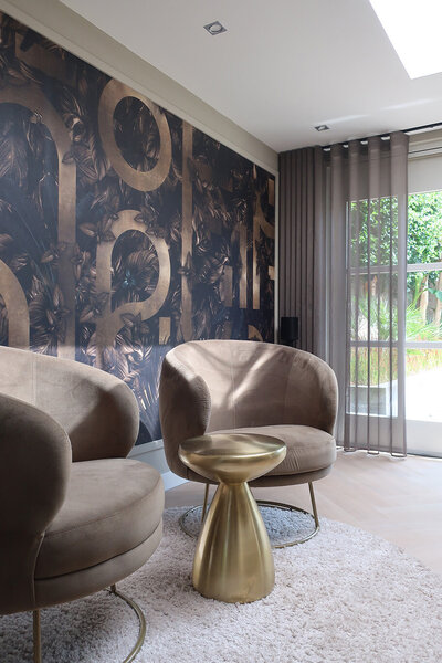 Eetkamer met ovale zwarte tafel, velvet stoelen en opvallende bloemenvaas als kleurrijk contrast