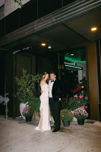 bride and groom standing outside the drake hotel with plants