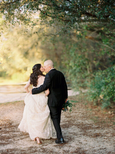 Bride and groom walk down a wooded path together