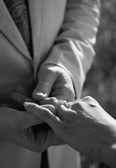 Groom puts ring on bride's finger at wedding ceremony in Colorado