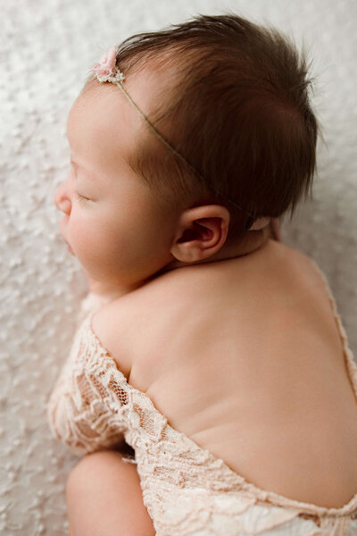 baby girl with a pouty lip sleeping in a floral bucket newborn photoshoot