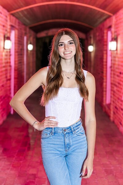 High school senior girl standing in tunnel at Lexington with a pink flash behind her. 