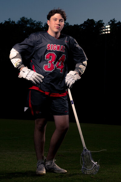 a high school lacrosse player poses for his signal mountain senior photos