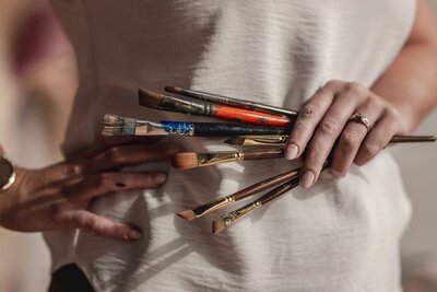A close up of hands holding paintbrushes