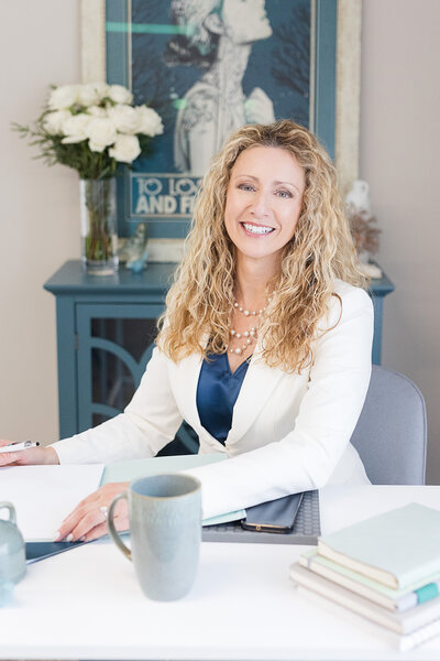 Kathleen sitting in her office smiling, writing in her journal