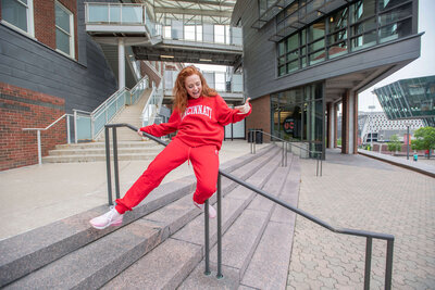 Model wearing game day apparel jumpsuit outdoors while sliding on a railing