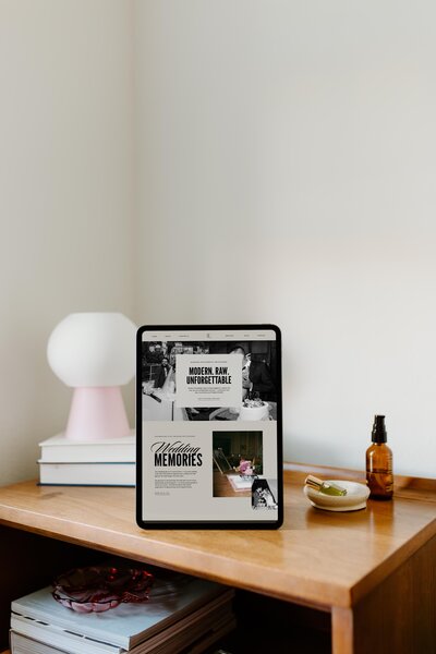 Tablet mit moderner Portfolio-Website für Hochzeitsfotografen auf Holzkommode.