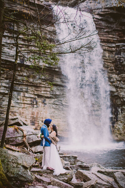 Engaged couple standing in front of a waterfall at minnewaska state park in new paltz ny
