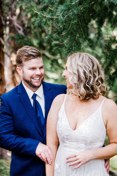 Groom looks at the bride while taking portraits in the mountains of Keystone. Colorado