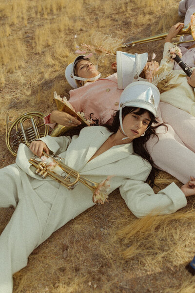 women laying on the ground in suits playing instruments