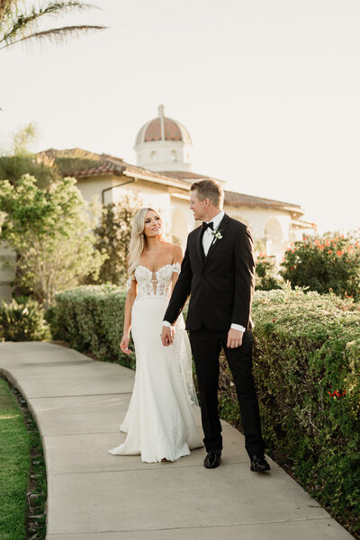 bride and groom walk down a path during golden hour romantics at spanish hills country club wedding in camarillo, ca