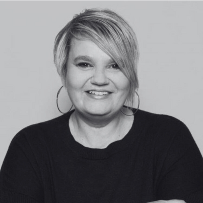 Jessica wearing a white blazer, smiling as she writes in her planner