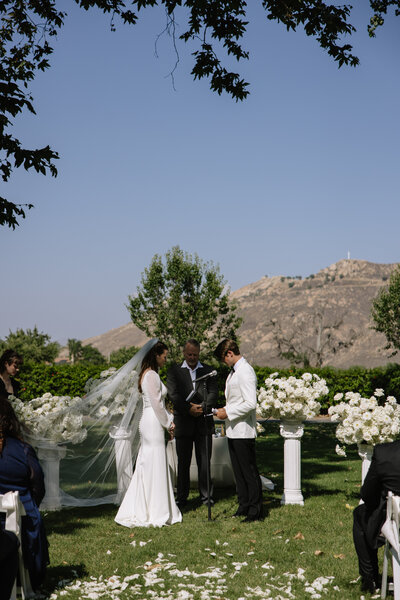 Payton and Evan standing at their ceremony while the officiant prays over them.