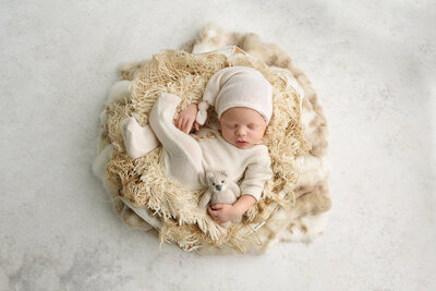 newborn in sleeping pose with creamy hat and outfit