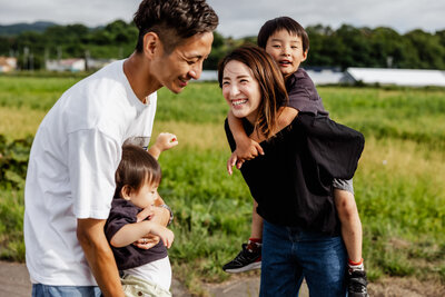A mother with her son on her back smiling at her husband
