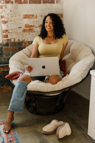 woman sitting with laptop on her lap while smiling