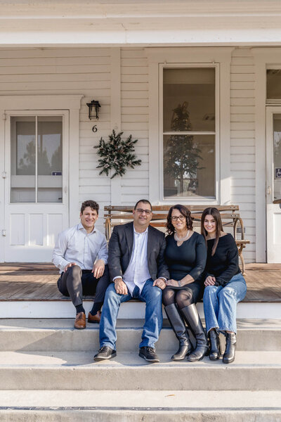 A family of four sitting on the steps of a historic white house near Katie Wheeler Library in Irvine