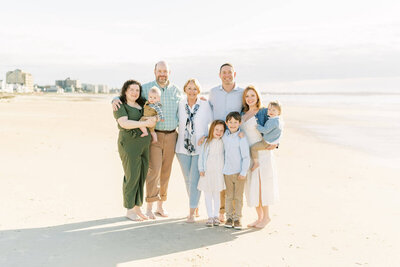 family of five pose for a photo on the beach in blue and white by carrie pellerin