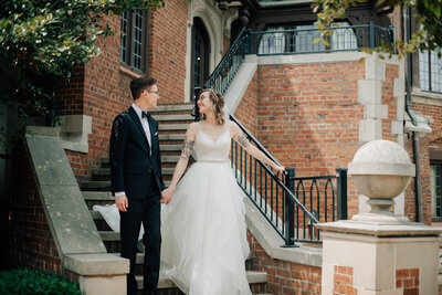 Bride and Groom walk hand in hand down a staircase at Rollins Mansion in downtown Des Moines.  Photo by Midwest wedding photographer, Anna Brace.