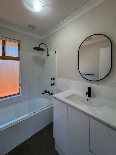 A modern bathroom with black fittings and white vanity.