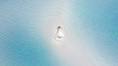 bride laying on the beach surrounded by water