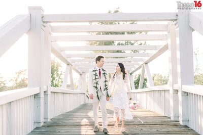 Bride and Groom go for a walk holding hands across a bridge at the Mike Ward Community Park in Irvine