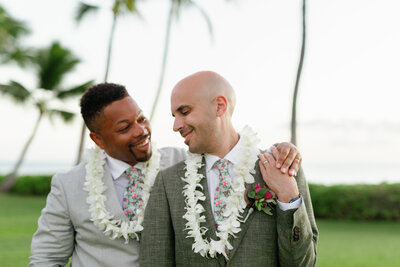 A person with their arm around their partner as they smile on their wedding day 