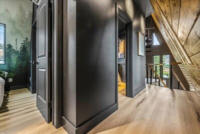 The nearly completed Perrine Hideaway A-frame cabin, featuring a black metal roof, large glass windows, and a rugged canyon backdrop