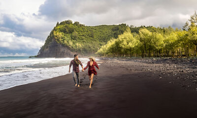 Couple running across beach for hawaii engagement photography