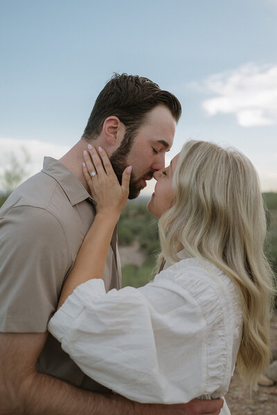 couple embracing on side of mountain range with Sedona landscape behind them