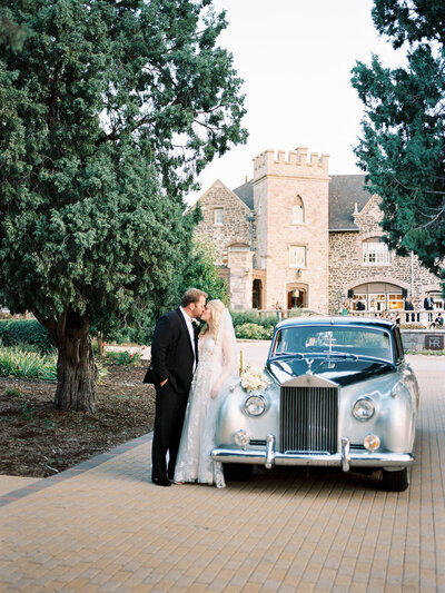 Happy bride and groom with a classic car at a castle fairytale bespoke wedding
