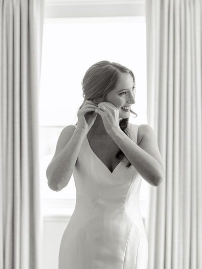 Black and white portrait of bride putting on her earrings