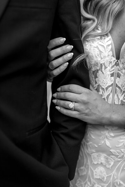 Bride and groom cuddled up against each other nose to nose and smiling at each other. The groom is wearing a black tux with a light pink bowtie. The bride is in a strapless white lace gown. The bride has a red ruby tiara in her half up and half down hair style. The couple is in front of a river dam at The Kings Mill wedding venue in Media Pa. Pa wedding photos, greater philadelphia wedding photographer, pa weddings, media pa wedding photos