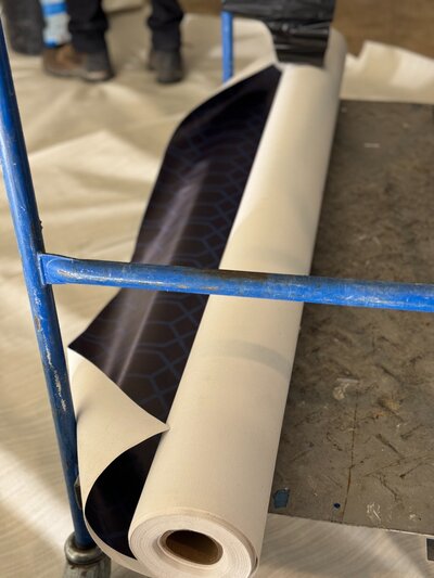 Close-up of bold navy wallpaper roll with geometric pattern used for ceiling installation.