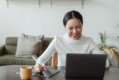 Woman smiling while on a video call with a laptop representing a supportive intake therapy session at Rooted & Nourished Psychotherapy