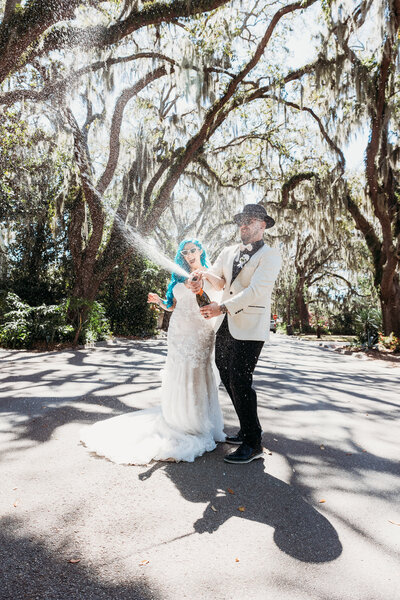 Champagne explodes around newlyweds under oak trees in St. Augustine, perfectly capturing their fun, bold, and alternative wedding vibe.