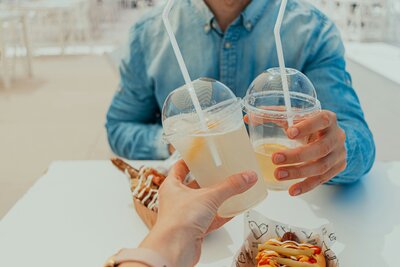 Two people cheers-ing with lemonades.