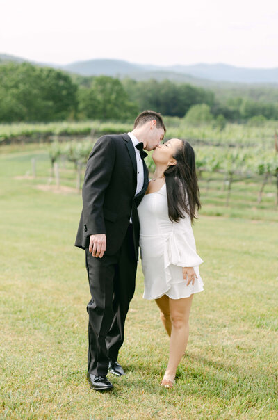 A bride and groom kiss at a vineyard.