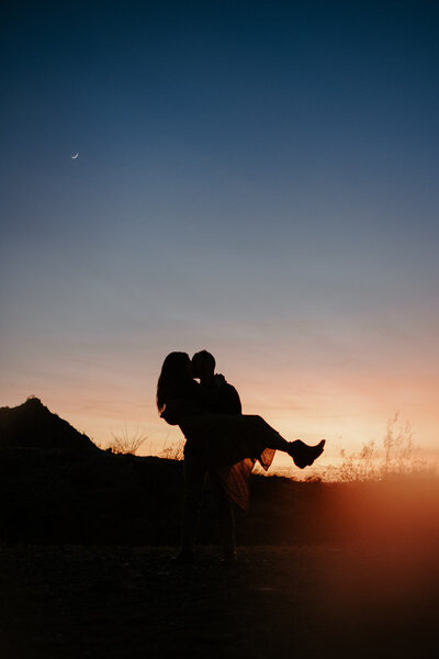 Parents kissing while holding newborn baby.