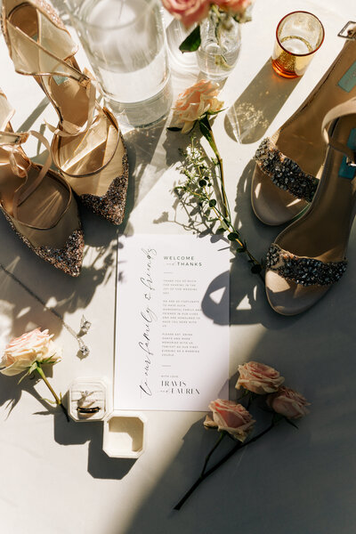 flat lay of wedding details, rings flowers, invites, and shoes