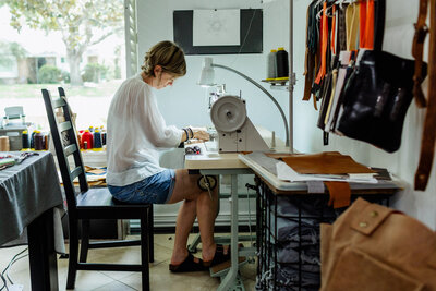 A leather bag artisan working on her creation using a sewing machine.